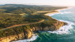 Aerial view of the Great Ocean Road itinerary route with coastal cliffs, turquoise ocean, and winding scenic drive in Victoria, Australia.