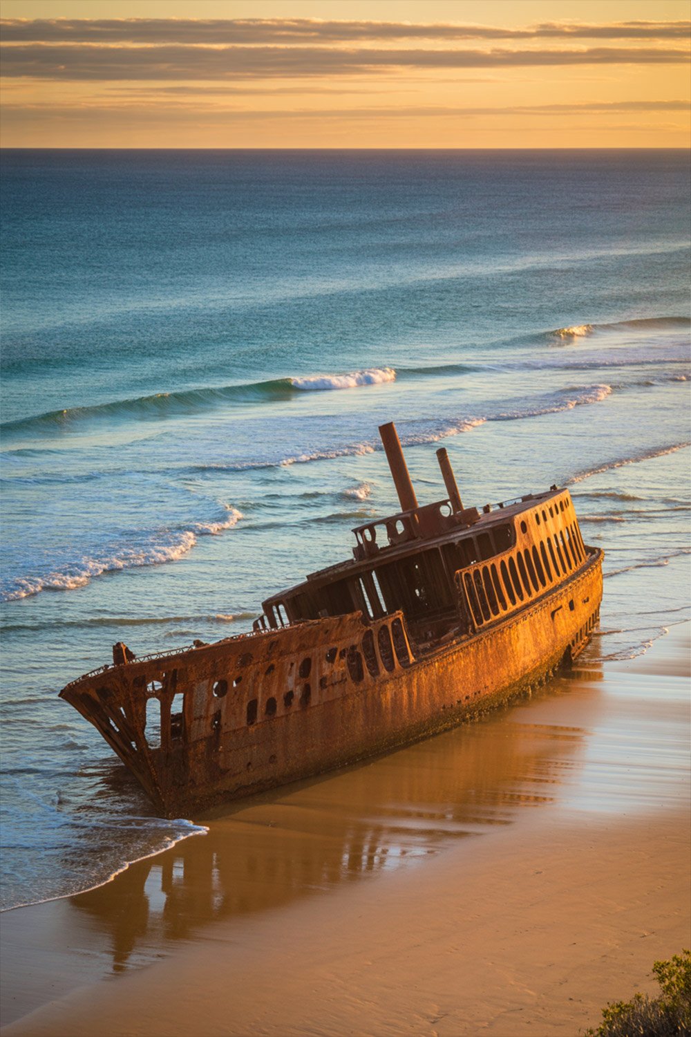 Maheno Shipwreck on Fraser Island at sunset with dramatic sky and rusting remains