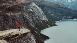 Tourist standing on Trolltunga cliff in Norway during the challenging Trolltunga hike guide from Odda.