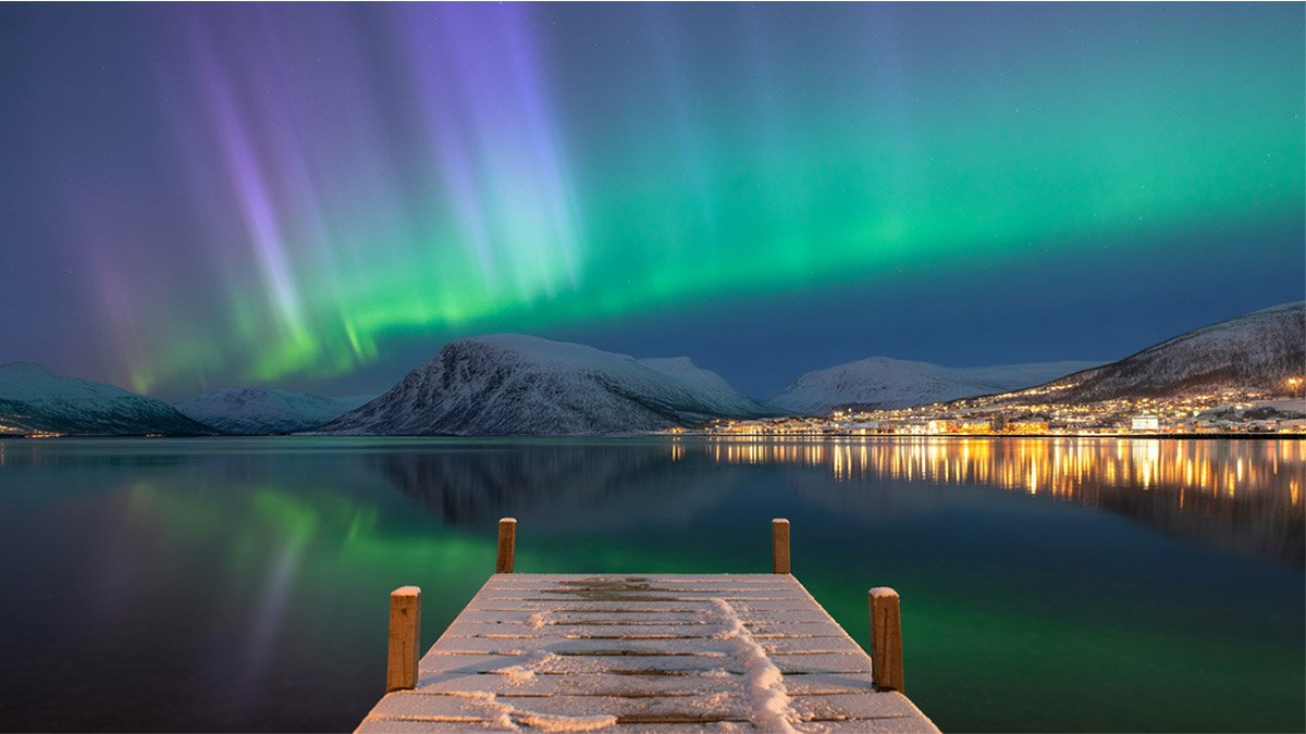 Tromsø Northern Lights Guide – Aurora over snowy fjord and mountains in Norway