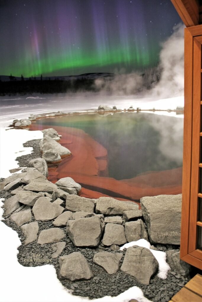 Aurora viewing at Chena Hot Springs Resort Alaska, showing steaming outdoor pools beneath vivid northern lights — part of Pathfinders Travel’s Fairbanks and Arctic Circle adventure guide.