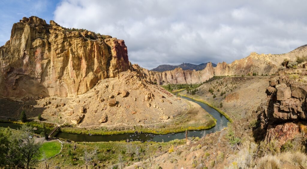 Dramatic cliffs of Smith Rock State Park rising above the Crooked River as it winds through the canyon in Central Oregon under cloudy skies