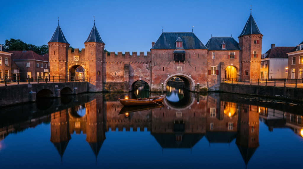 The Koppelpoort medieval water gate reflected in the canal in Amersfoort, Netherlands at dusk