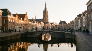 Delft Netherlands Markt square with the New Church tower and a canal at golden hour