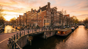Amsterdam canal at golden hour with gabled houses and bikes, Netherlands travel guide hero image